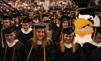 graduates with a mascot in the background