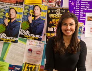 student smiling with event posters in the background