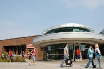 students walking by a modern building with circular section