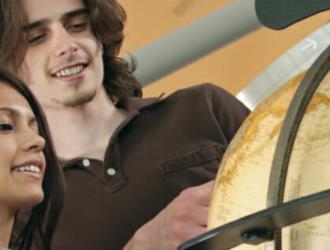 two students looking at a globe together