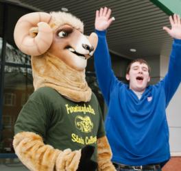 mascot and student cheering near a college building