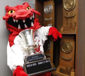 mascot with trophy near award cases