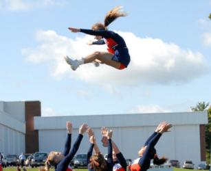 cheerleader being tossed in the air outdoors