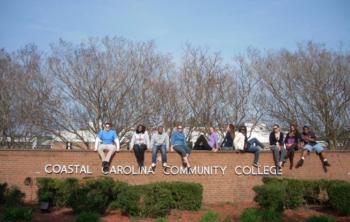 students sitting on a brick wall with 'coastal carolina community college'