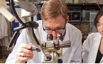 two people with a microscope in a lab