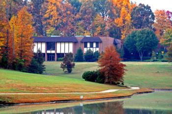 building with fall trees reflected in a pond