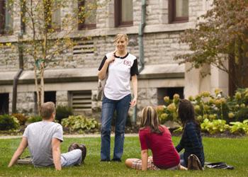 student standing on grass with others seated around