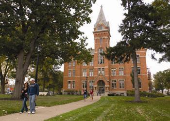 people walking near a brick building with a tower