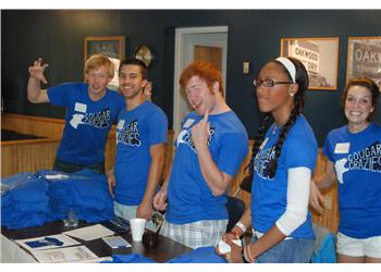 students in blue shirts waving at the camera