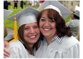 two graduates smiling and hugging