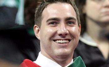 smiling graduate in red and green regalia