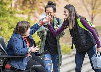 three students laughing and gesturing high-five