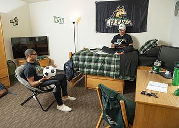 students in a dorm room with one playing a guitar