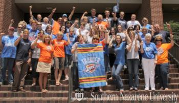 group in blue shirts waving under 'Southern Nazarene University'