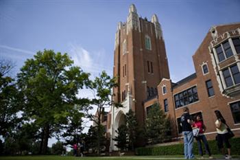 students by a tall campus building with trees