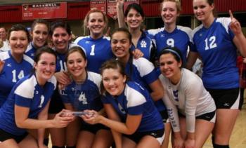 volleyball team celebrating with a trophy