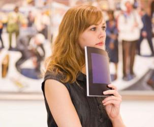 woman holding a booklet, artwork in background