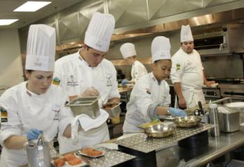 students in chef uniforms cooking in a kitchen