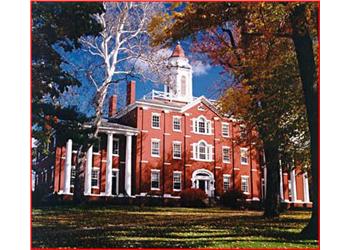 historic red brick building with white columns and autumn trees