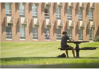 student at outdoor table on campus