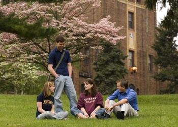 students on grass with flowering trees and building