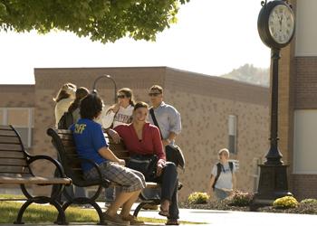 people chatting on bench near campus building