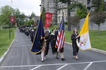 graduation procession with flags on campus road
