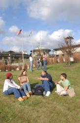 students sitting on grass with campus building behind