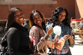 three smiling female students holding snacks