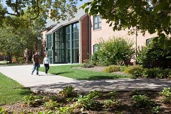 students walking by campus building in autumn