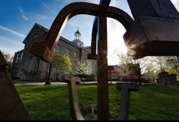 art sculpture on campus with a building and sunburst