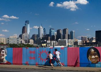 people jogging by colorful mural and city skyline