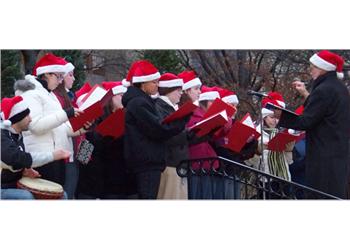 choir singing outdoors in santa hats