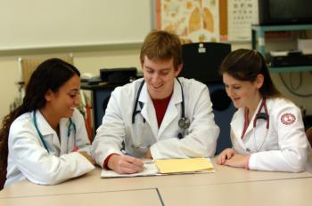 nursing students in lab coats studying together