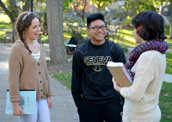 three students talking with books on campus