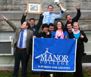 group celebrating with manor college banner