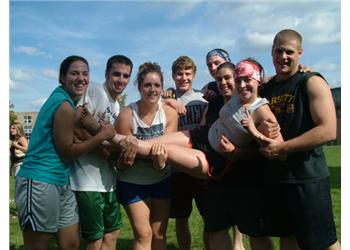 students lifting a person outdoors in sunshine