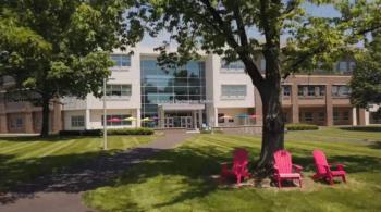 tree and red chairs in front of campus building