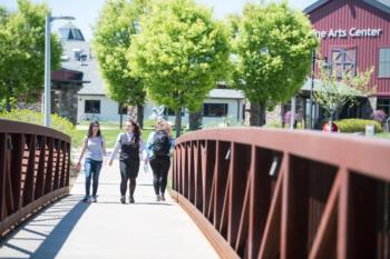 students walking over a bridge towards Fine Arts Center