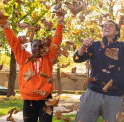 students throwing leaves in air during autumn