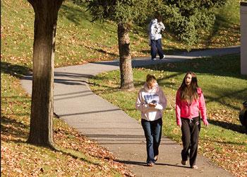 two students walking on leafy campus path