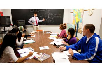 teacher in front of students at a round table