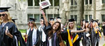 graduates celebrating, one holding diploma