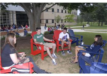 students chatting on red and blue chairs outdoors