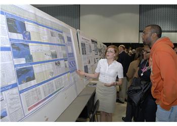 student presenting a poster to visitors