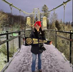 student holding sign on suspension bridge