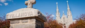 stone sign 'VILLANOVA' with church in background