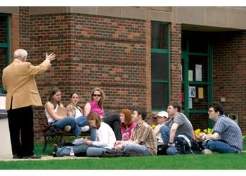 students sitting on grass with an instructor outdoors