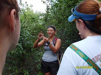 student showing specimen to peers outdoors