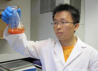 student in lab coat inspecting liquid in flask